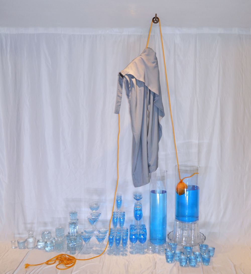 Clothing hanging above a selection of glass receptacles filled with blue liquid
