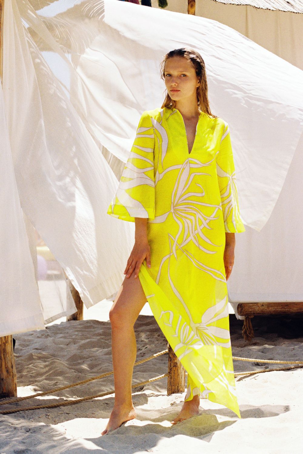 Woman on a beach wearing a yellow kaftan with a white pattern