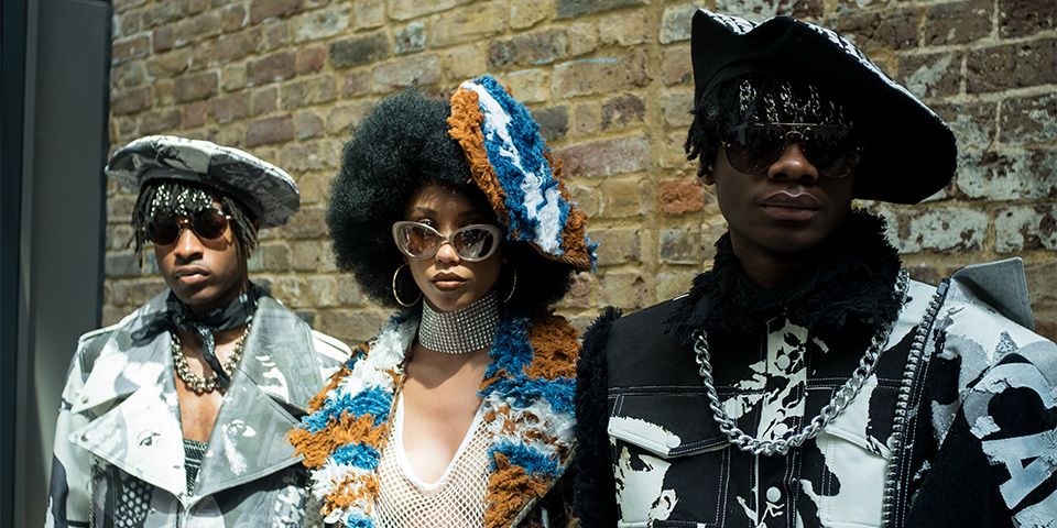Three models stood next to each other wearing sunglasses and designs by Tolu Coker