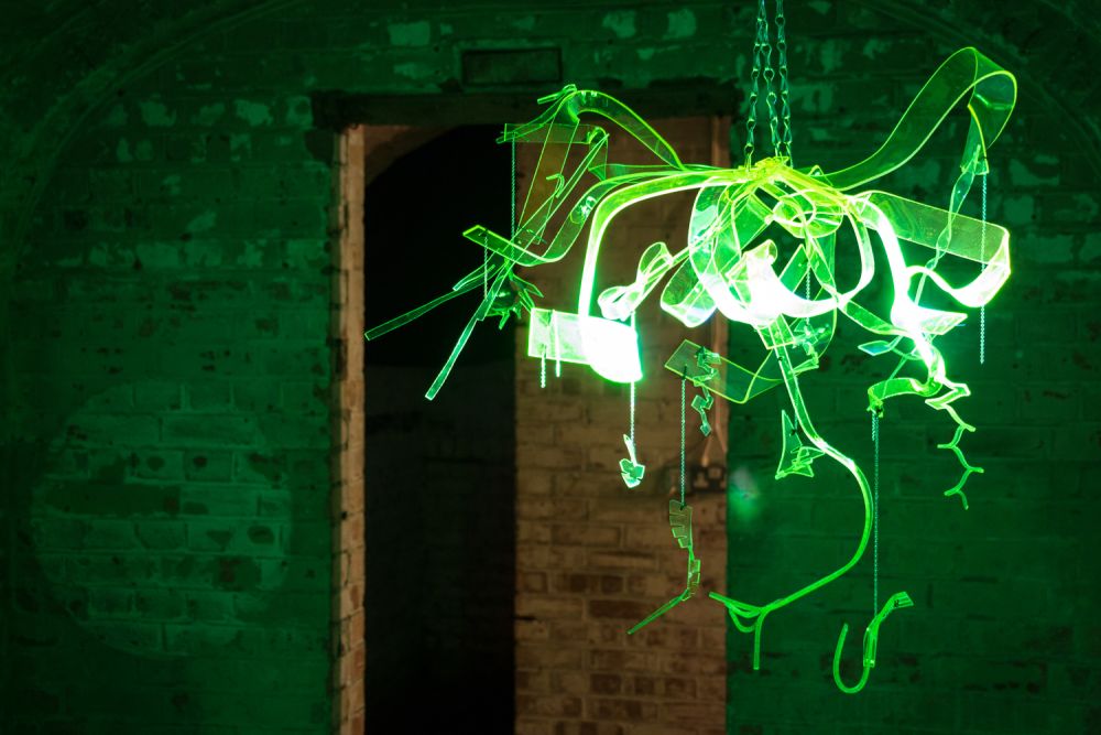 A transparent green hanging sculpture is illuminated