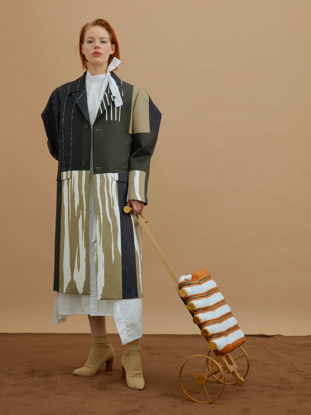 Ginger model standing holding onto bottle holder with wheels