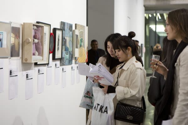 Photograph of visitors reading the handouts and looking at the work in the silent auction