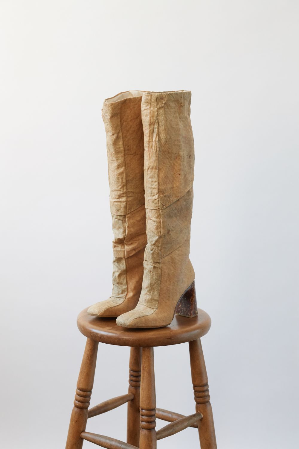 Beige knee high boots on a wooden stool