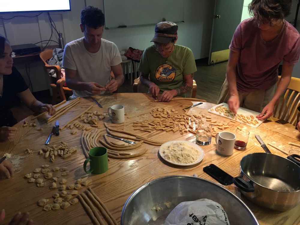 people around a table making pasta