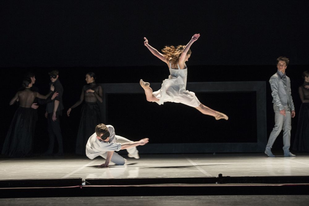 two dancers leaping in a dark theatre