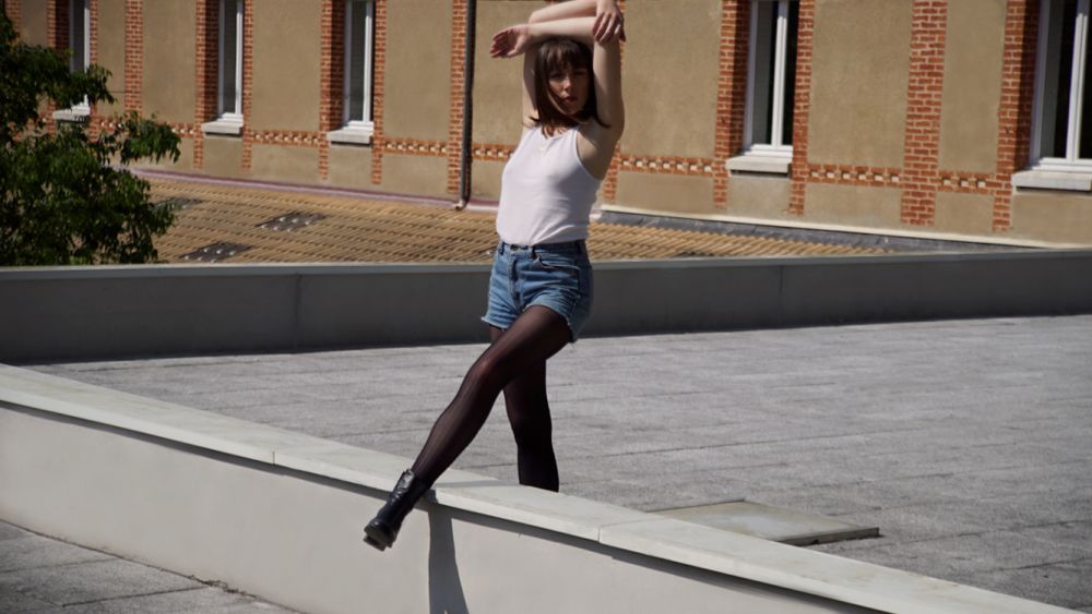 Female dancing on rooftop with pair of tights on