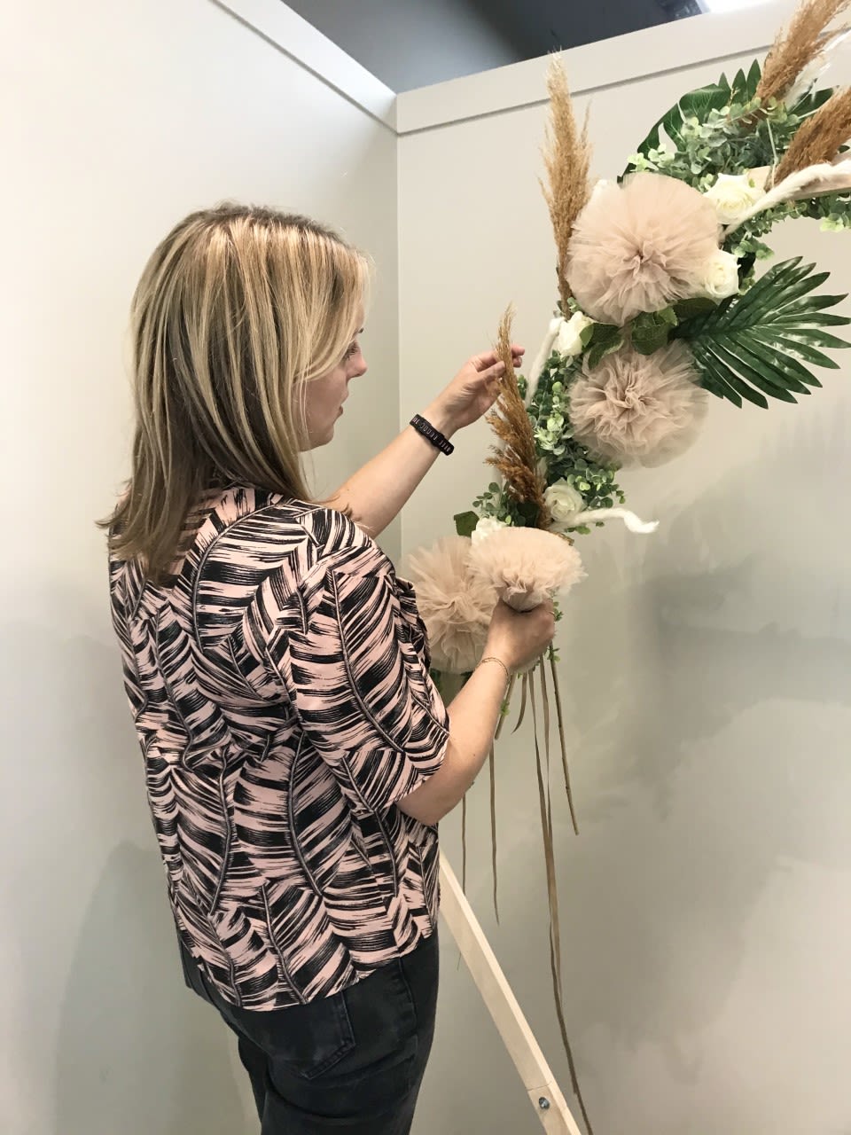 A photo of Sarah Manning standing and fixing together a floral arrangement.