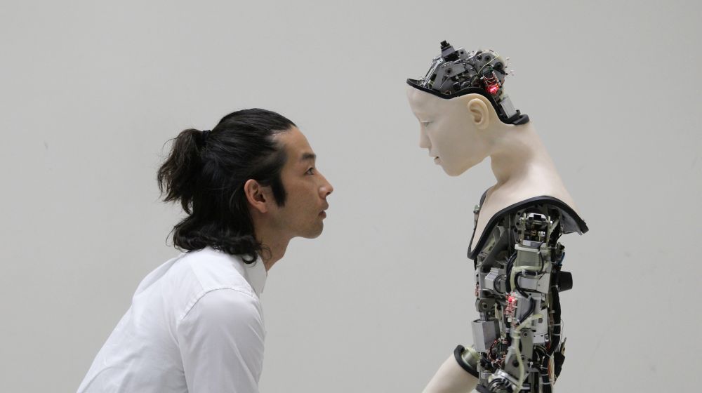 Japanese man face to face with robot both side profile