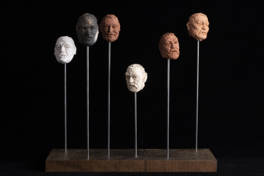 A series of heads made from clay displayed on plinths 