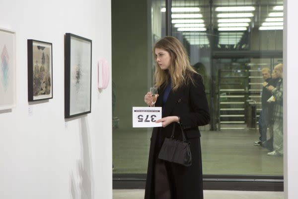 Photograph of a woman looking at the installed work in the gallery