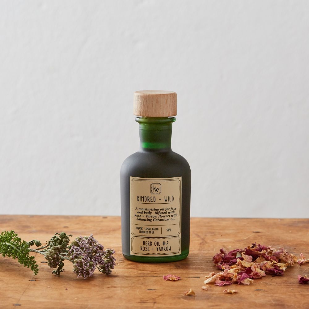 An image of an organic rose oil in a green glass bottle created by the brand Kindred + Wild