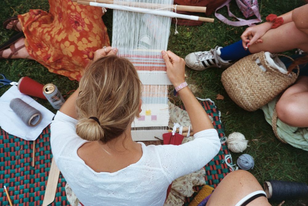 A small group at a festival learning to weave using hand loom