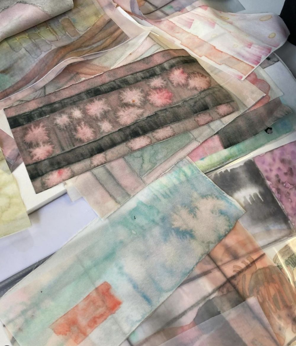 Samples of chiffon fabric in a watercolour painted effect are scattered on a surface