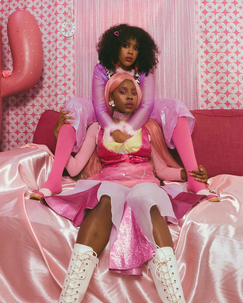 Photograph of two black models in a pink room wearing pink outfits
