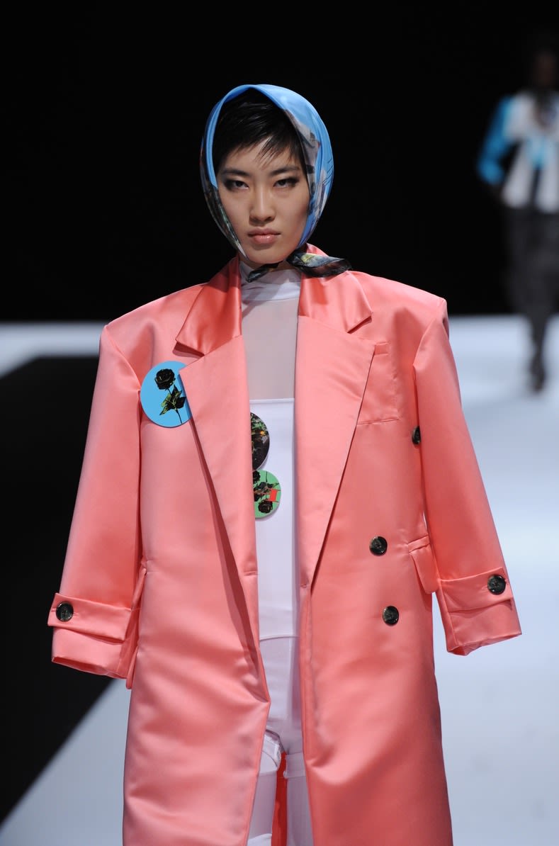Female model wearing salmon jacket and blue headscarf designed by Hannah Ross