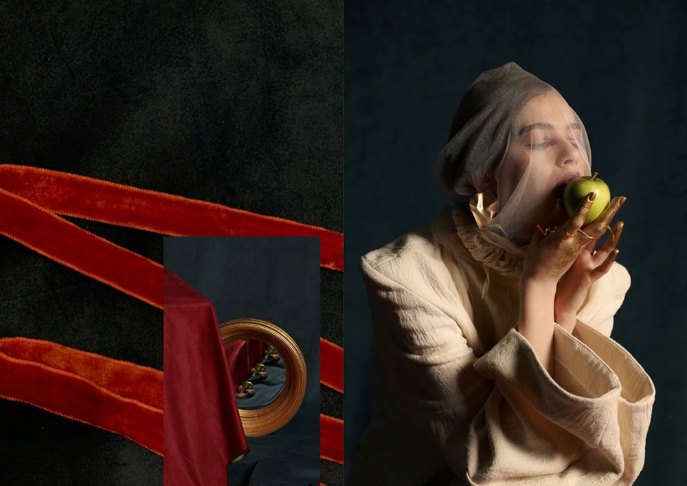 Female model with a veil on eating an apple wearing a white suit and sitting on a red cloth