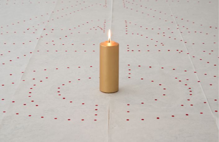 candle on floor with red dot stickers on floor around it