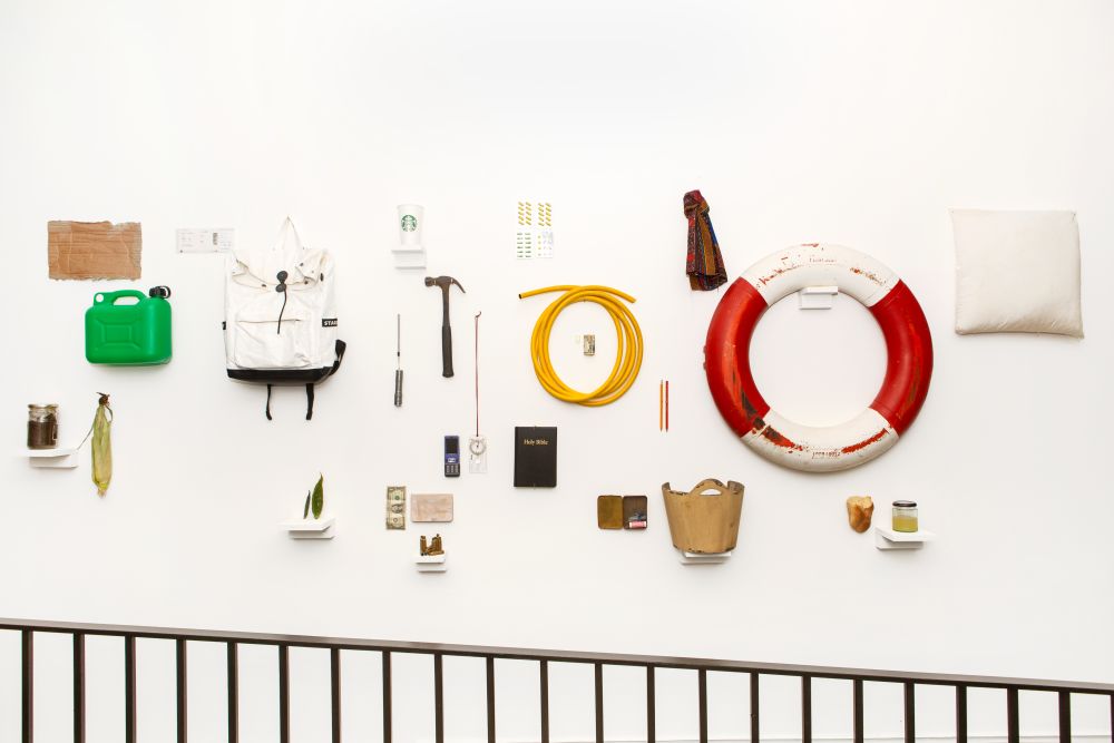 Various objects including a rucksack, a life ring and other tools mounted on the wall as part of Emergence exhibition