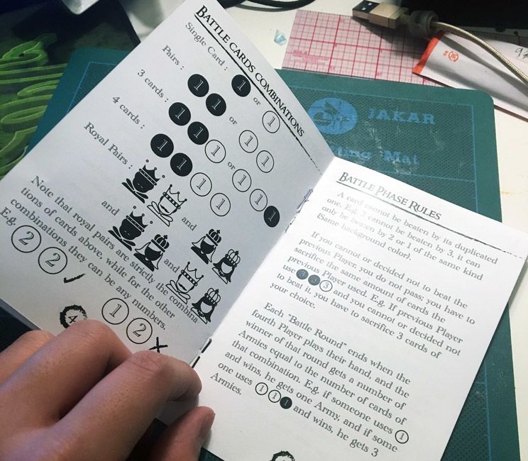 An open rule book for a game designed by student Chris Li. The book shows infographics on Battle Card Combinations. 