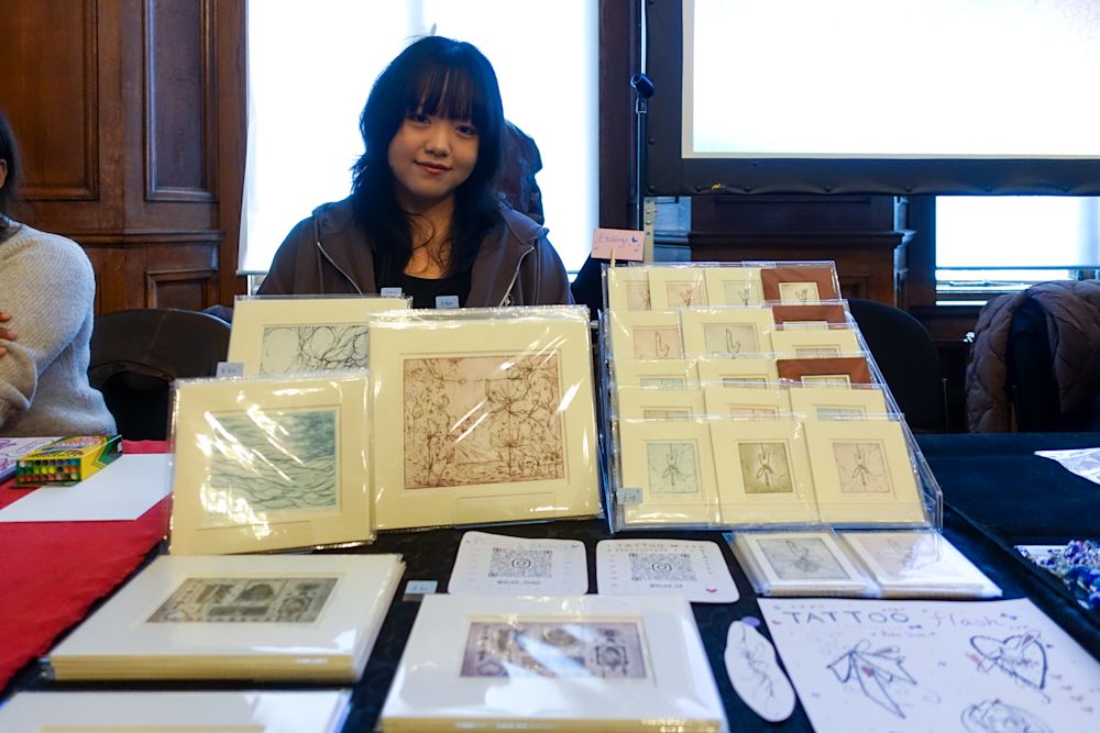 A student selling her work and smiling at the camera