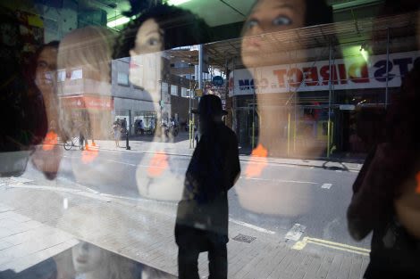 a window of wigs on female manniquins with the street reflection in the window