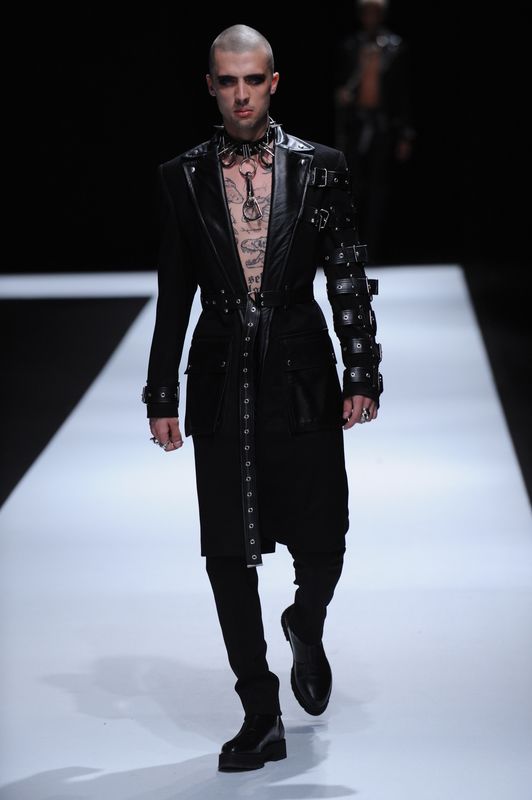 Topless male model with black longline jacket decorated with leather and silver studs
