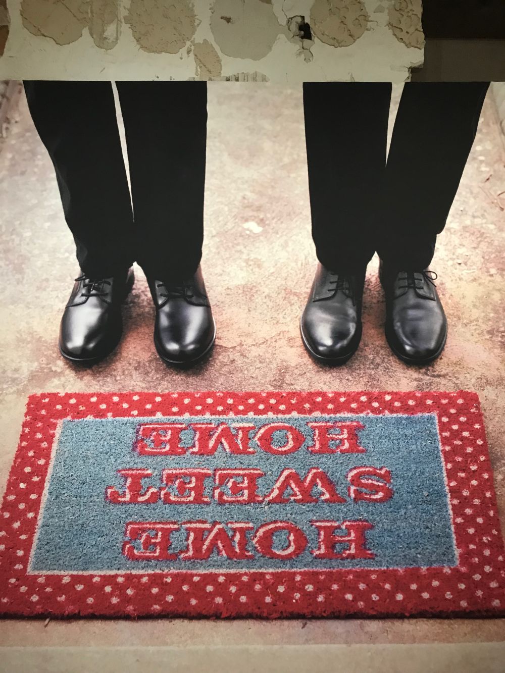 two pairs of polished shoes stepping on rug with the words home sweet home imprinted