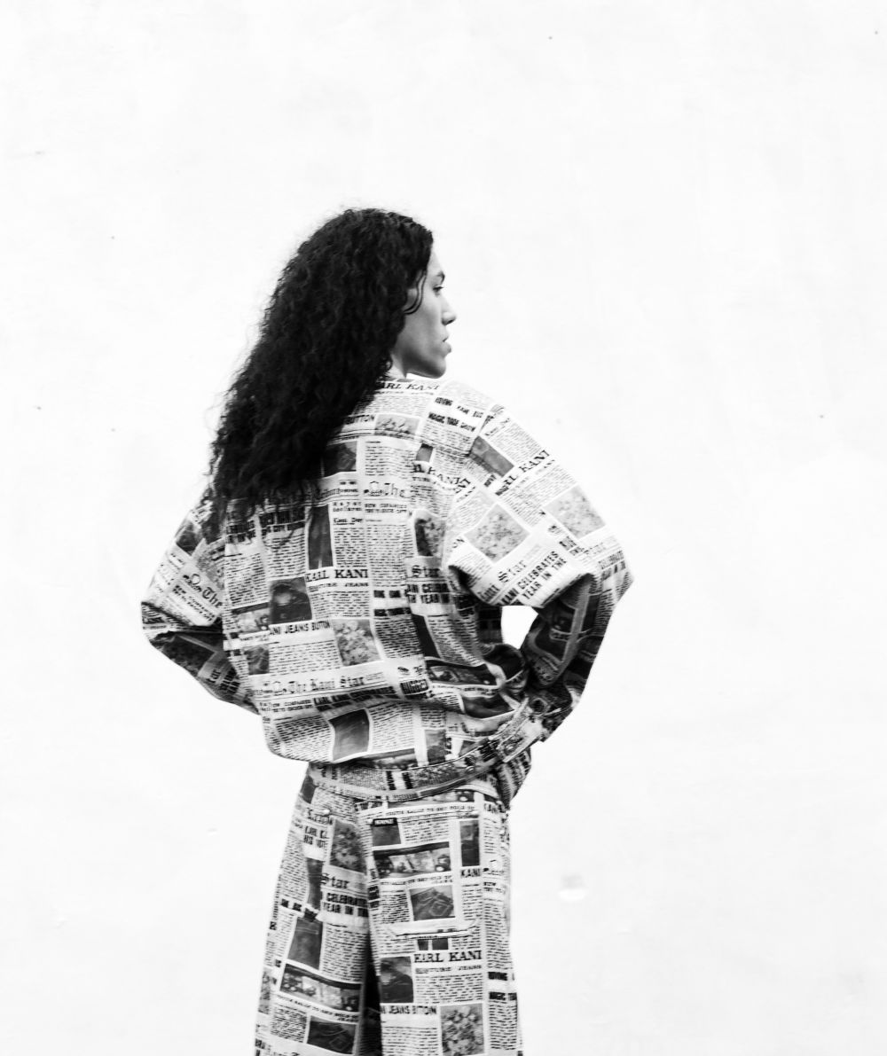 Photograph of a man wearing a newspaper print denim jacket, shot from the back