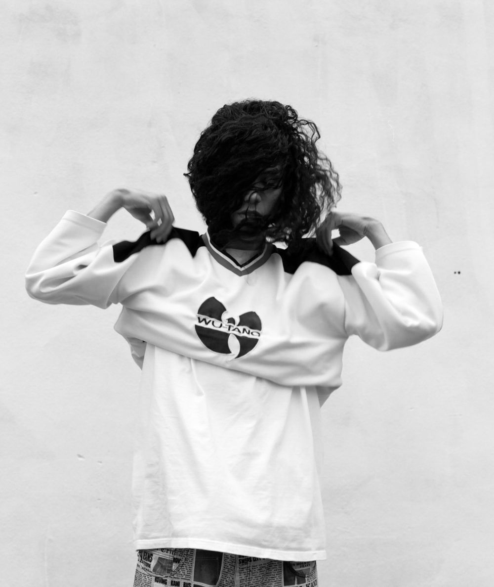 Photograph of a person putting on a sweat shirt with a Wu-Tang logo