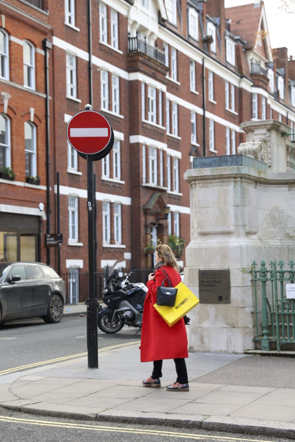 woman in red coat next to a red stop sign in street