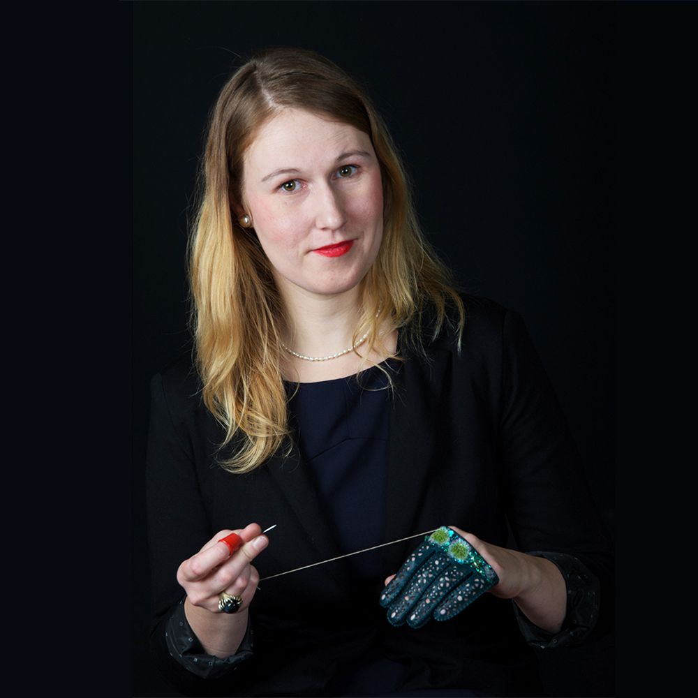 Portrait photograph of tutor, Riina Õun, working on a glove.