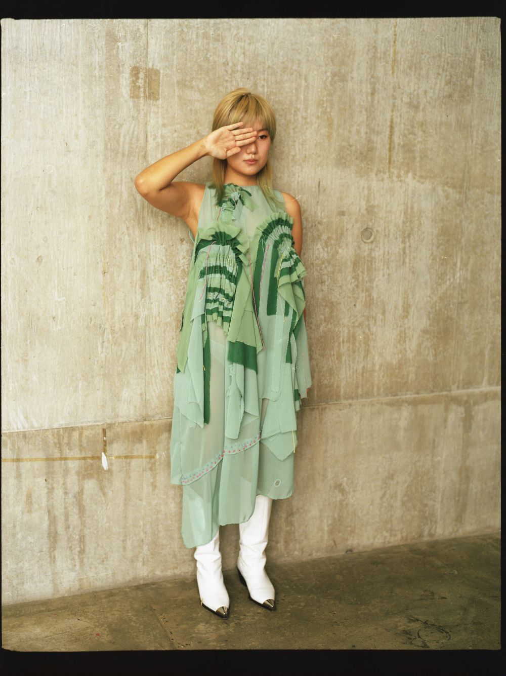 A model in Emily's fashion design of a long green shirt dress. 