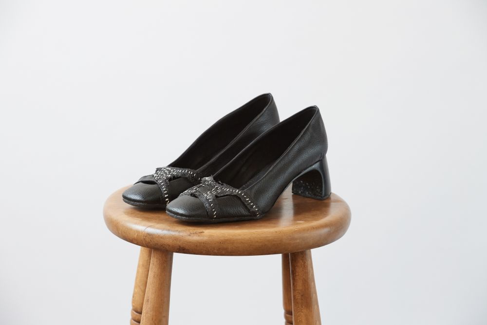 Black heeled mules resting on a wooden stool