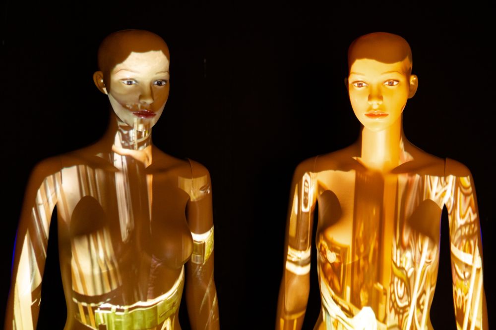 two mannequins with light projections covering them.