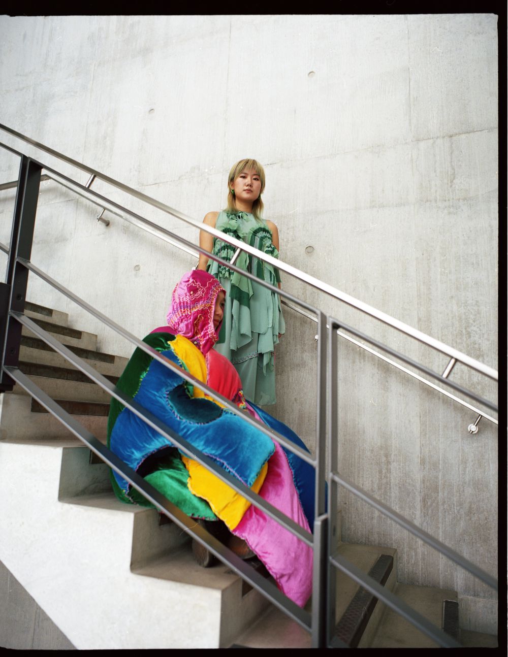 2 models sitting on the stairs at CSM, wearing creations from Study Abroad on BA Fashion