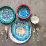 Photograph of several bowls and plates decorated with blue and teal patterns and writing