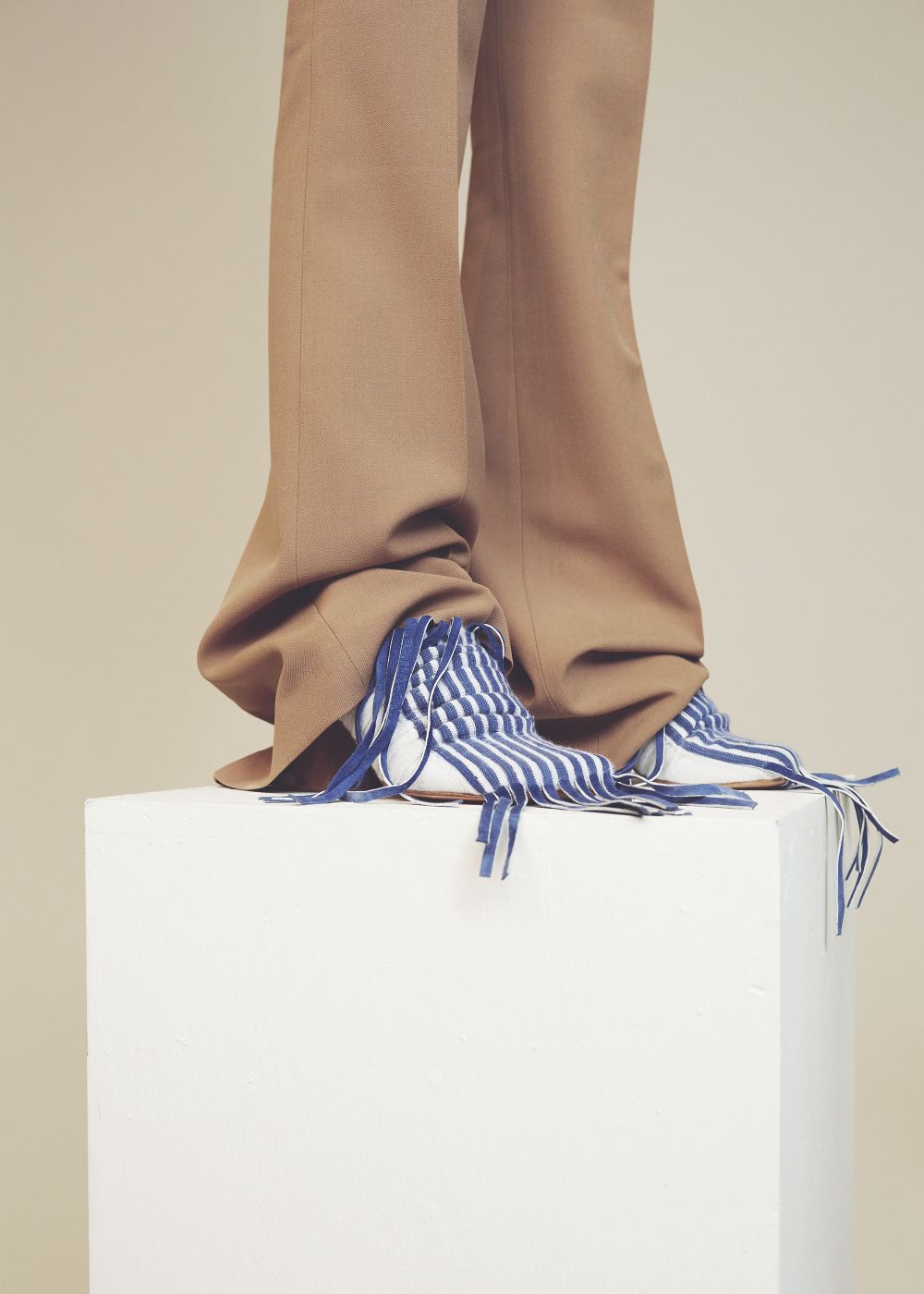 Tan baggy trousers worn with mid heel white and blue striped pointed shoe