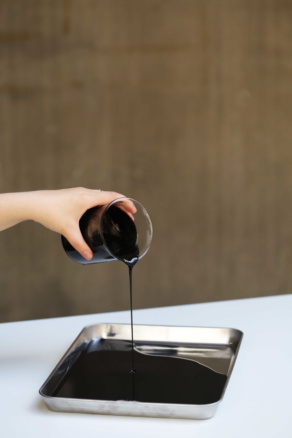 Hand pouring glass jar of dark liquid