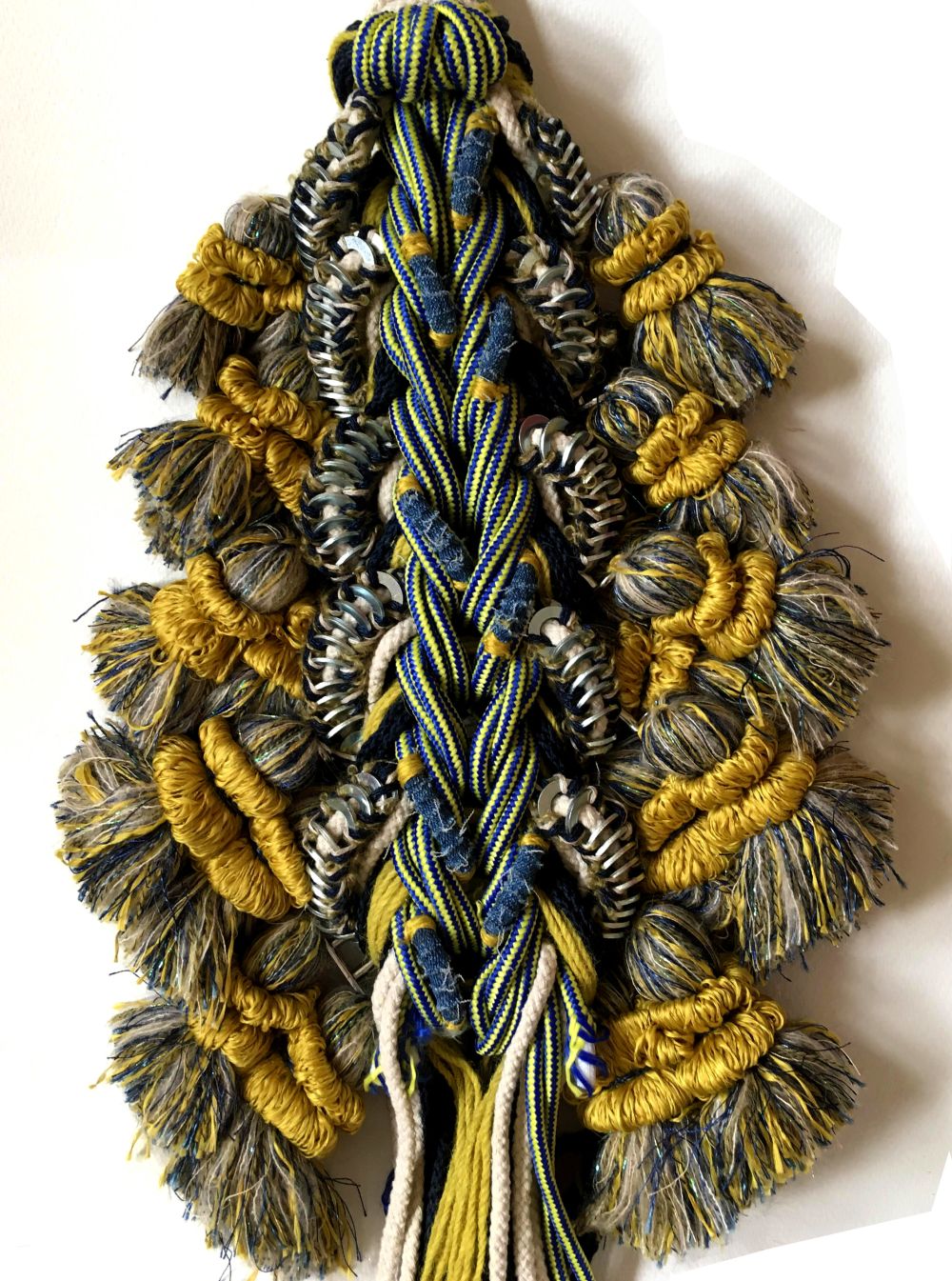 A row of tassels and fringing in gold, yellow, blue and green materials