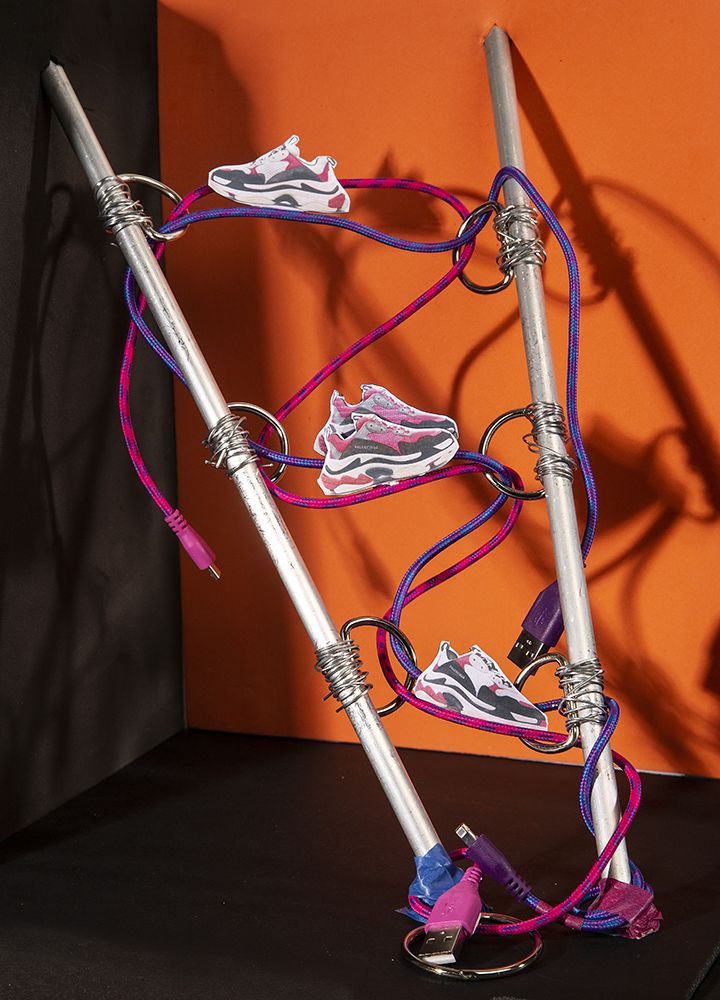 Work by Visual Merchandising - Interiors students, taken by Sarah Manning. Photographs of pairs of trainers perched on USB wires coiled around two metal spikes.