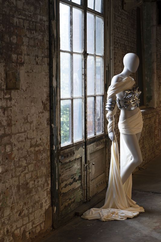 Mannequin in white and silver outfit next to a window