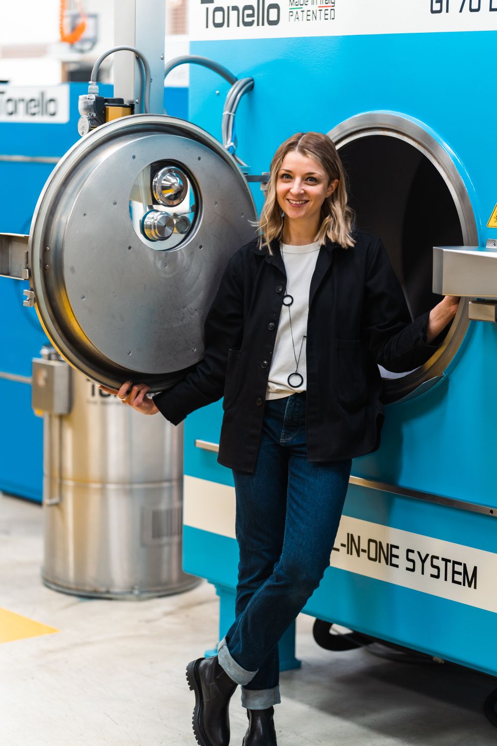 a person is leaning and posing next to a big machine for dying clothes
