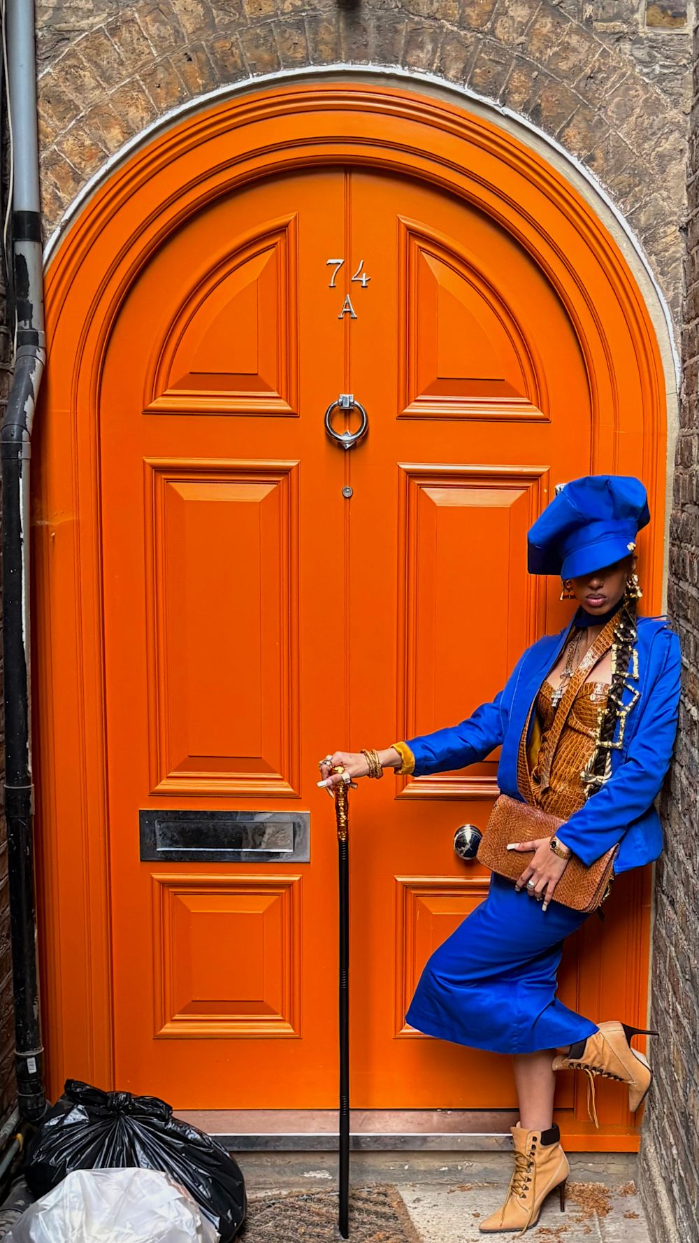 woman in blue stood in front of an orange door
