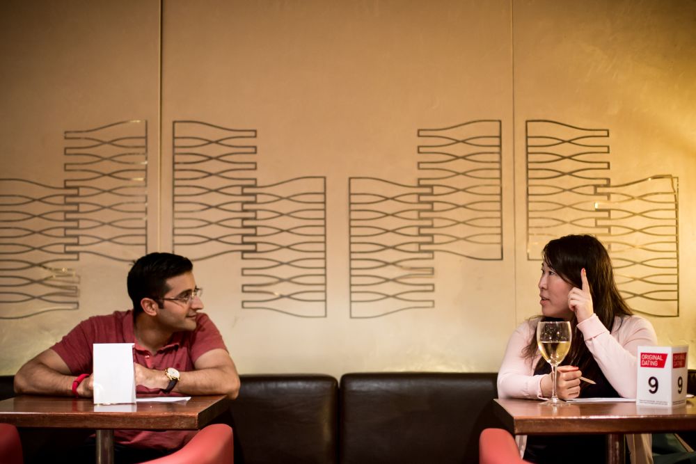 a man and woman talking across tables