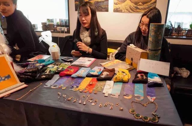 Two women sat behind a table with things for sale
