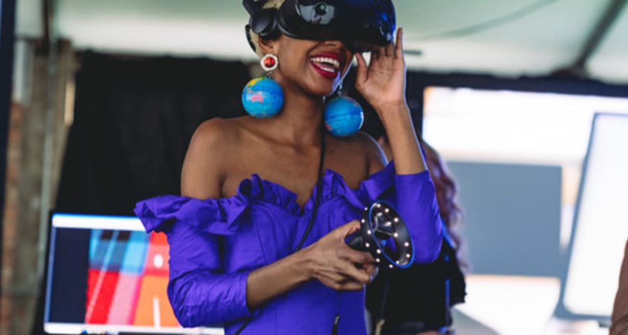 A woman in a blue dress wearing a VR headset.