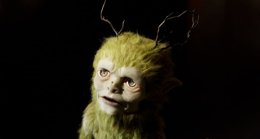 Green furry creature with antlers stares into the light