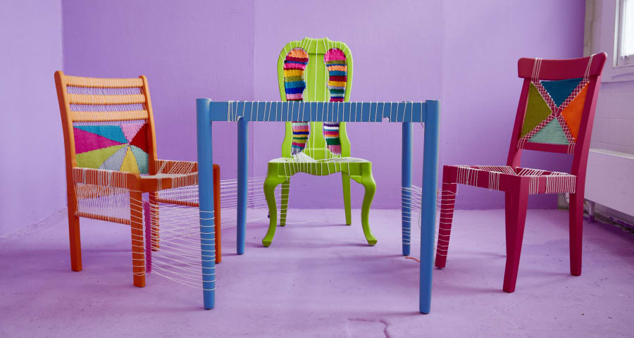 Two wood chairs and a table, woven in multi colour threads