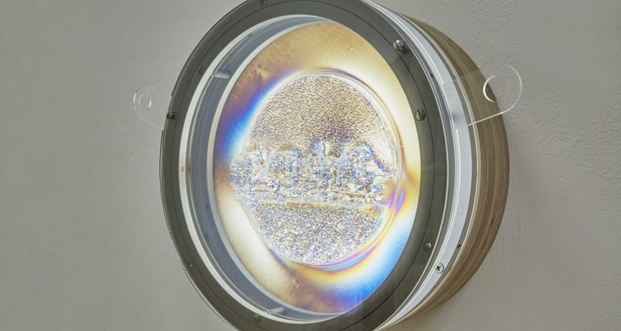 Camera lense attached to a wall with a light shining through with glitter and liquid