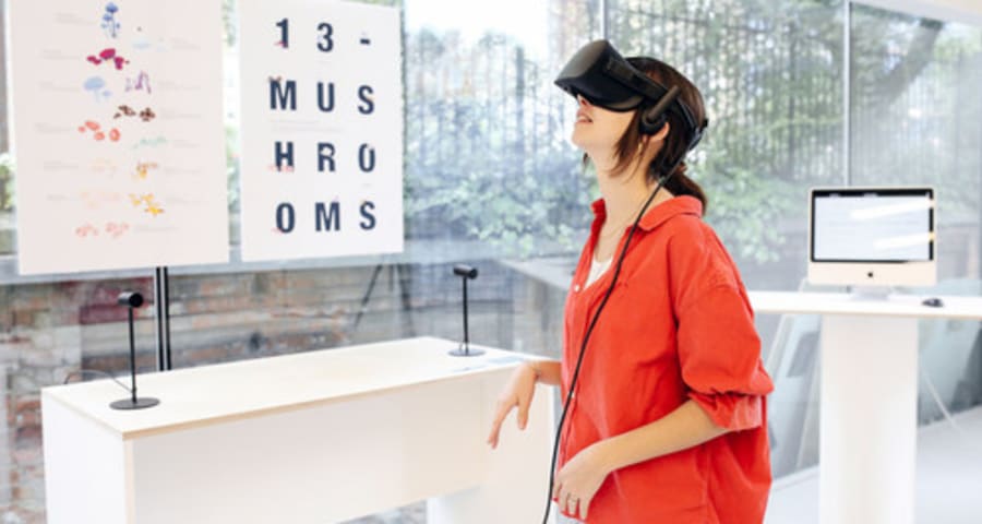 A person wears VR goggles and typography posters are attached on the wall